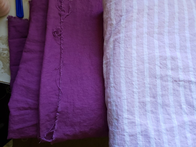solid purple fabric displayed next to lilac and ivory stripe fabric